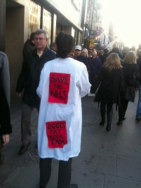 Frau mit Save The NHS und Boots Pay Your Tax auf ihrem Overall